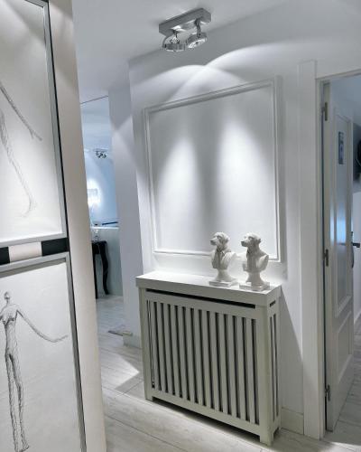 um quarto branco com esculturas numa mesa com um espelho em Apartamento Platas Centro em Ribadesella
