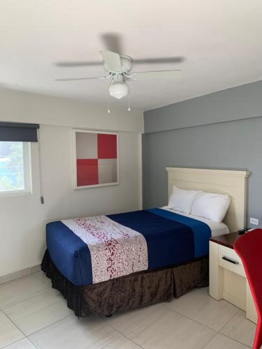 a bedroom with a blue bed and a ceiling fan at La Purisima Hotel in La Paz