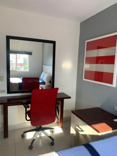 Cette chambre comprend un bureau, une chaise rouge et un miroir. dans l'établissement La Purisima Hotel, à La Paz