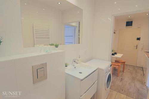 uma casa de banho branca com um lavatório e uma máquina de lavar roupa em ul Monte Cassino 16/11 em Świnoujście