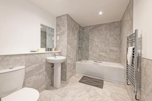 a bathroom with a toilet sink and a bath tub at Gospel Heights by Guestz in Heswall