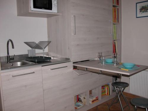 cocina con fregadero y encimera con taburetes en studio au pied des troglodytes, près de la plage, en Saint-Chamas