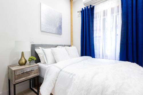 - une chambre avec un lit blanc et des rideaux bleus dans l'établissement 317-1AN - New Modern 1BR W&D Walk to Central Park, à New York