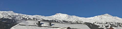 a snow covered mountain range with a building in the foreground at Zentral, Ruhig, Sonnig, Modern in Lenzerheide