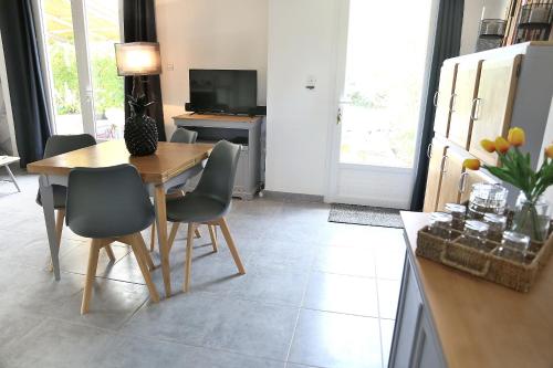 een keuken met een houten tafel en stoelen en een televisie bij Jolie villa loc-saisonnière - la petite cocagne in Alleins