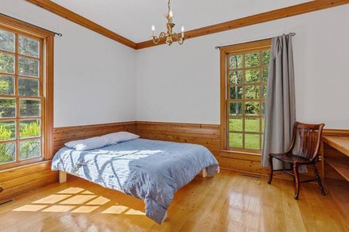 a bedroom with a bed and a chair and windows at The Swan in Petersburg