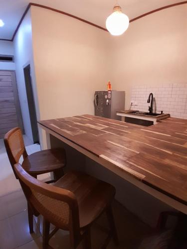 a kitchen with a wooden counter and two chairs at anik homestay & dormy Batukaras in Batukaras