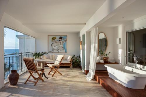 La salle de bains est pourvue d'une baignoire, d'une table et d'un canapé. dans l'établissement Casas Brancas Boutique Hotel & Spa, à Búzios