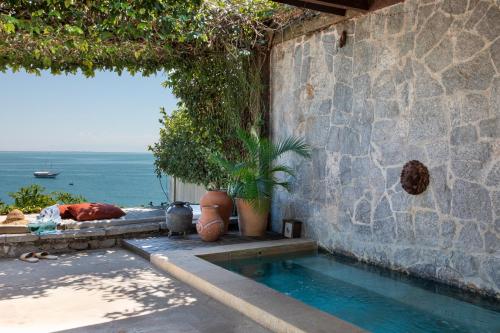 ein Haus mit einem Swimmingpool neben einer Steinmauer in der Unterkunft Casas Brancas Boutique Hotel & Spa in Búzios
