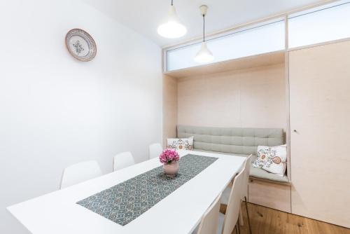 a dining room with a white table and a vase of flowers at Castle Wall Apartment in Bratislava