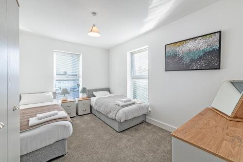 two beds in a room with white walls and windows at Gospel Heights by Guestz in Heswall