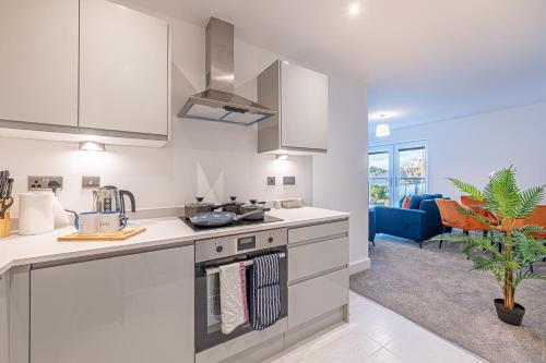 a kitchen with a stove top oven next to a living room at Gospel Heights by Guestz in Heswall