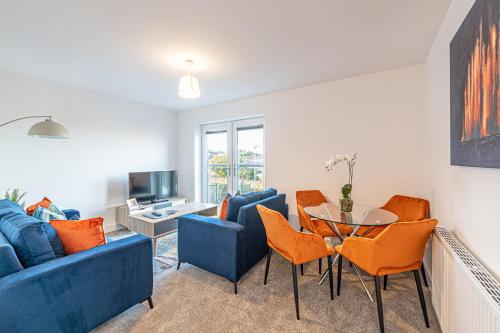a living room with a blue couch and orange chairs at Gospel Heights by Guestz in Heswall