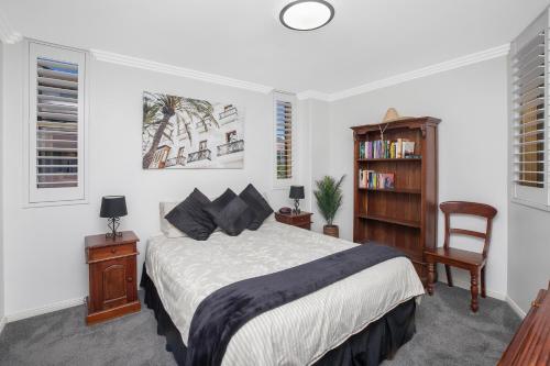 - une chambre avec un lit, une chaise et une étagère dans l'établissement Riviera 203, à Port Macquarie