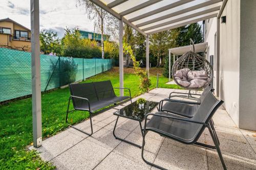 two chairs and a swing on a patio at Apartamenty Wczasowa - z widokiem na góry, parkingiem, rowerownią in Kudowa-Zdrój