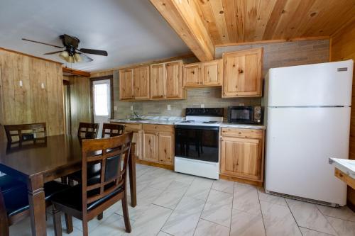 a kitchen with a white refrigerator and wooden cabinets at Depe Dene Lakeside Resort in Lake George