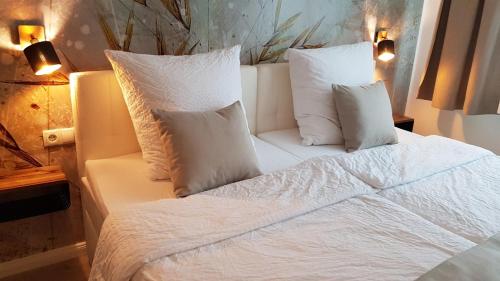 a bed with white sheets and pillows in a room at Bergische Idylle in Overath