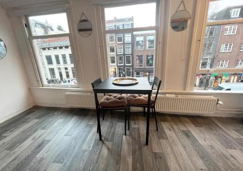 a table and chairs in a room with windows at Studio's in the Center of Amsterdam with Canal View! in Amsterdam