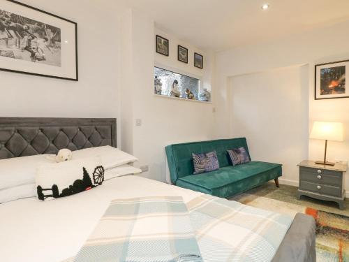 a bedroom with a bed and a green chair at Maples Annex in Heanor