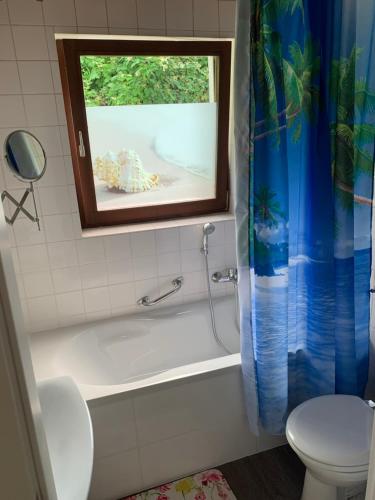 ein Bad mit einer Badewanne, einem WC und einem Fenster in der Unterkunft Apartment im Herrenwäldchen in Brombachtal