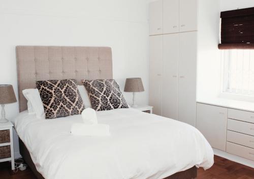 a white bedroom with a large white bed with pillows at Villa Capri in Cape Town