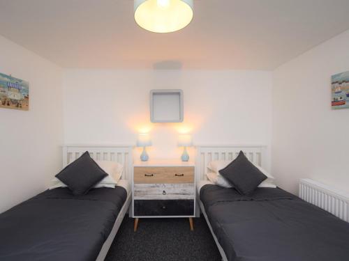 a bedroom with two beds and a nightstand with lights at 2 bed in Brixham 75549 in Brixham