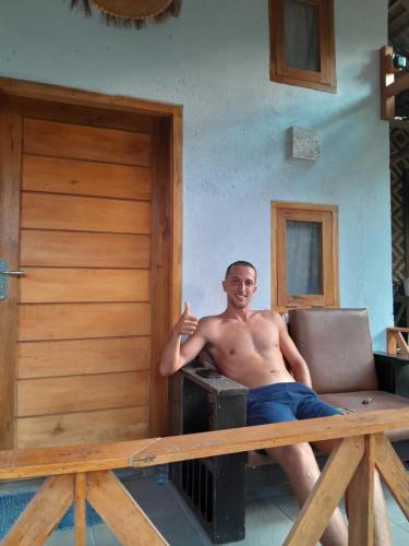 a man sitting on a couch in a house at anik homestay & dormy Batukaras in Batukaras