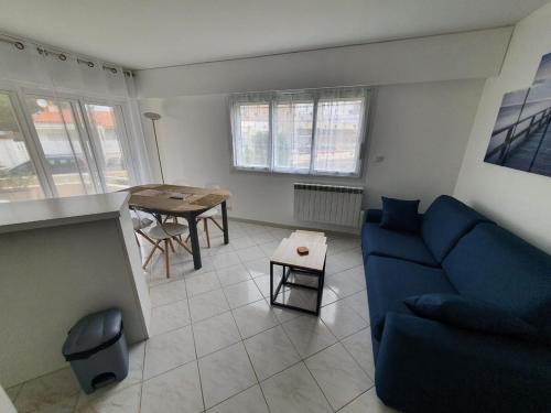 ein Wohnzimmer mit einem blauen Sofa und einem Tisch in der Unterkunft Appartement "Le Grand Bleu" - A deux pas de la côte sauvage - 4 pers in Les Sables-dʼOlonne