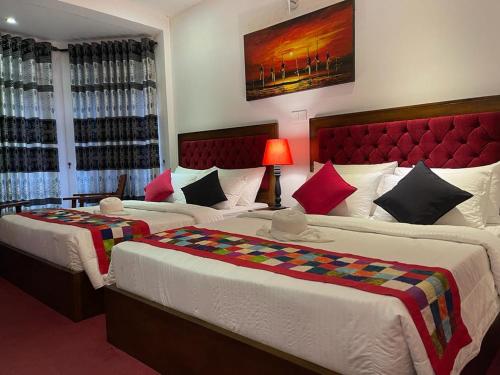 een slaapkamer met 2 bedden en een rood hoofdeinde bij The Rosedale Grand Bungalow Nuwara Eliya in Nuwara Eliya