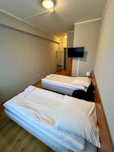 a room with two beds and a tv on the wall at Hotel Akor in Bydgoszcz