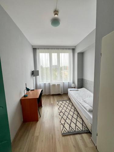 a bedroom with a bed and a desk and a window at Hotel Akor in Bydgoszcz