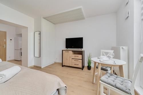 a bedroom with a bed and a tv and a table at New Studio Tęczowa with FREE GARAGE Wrocław by Renters in Wrocław