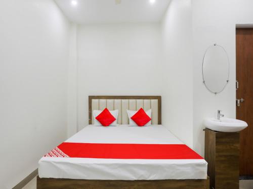 1 dormitorio con cama con almohadas rojas y lavamanos en OYO Flagship Hotel Rahul Service Appartment 2, en Nagpur