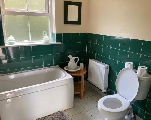 y baño con bañera, aseo y lavamanos. en Glencolumbkille House - Self Catering Rooms en Glencolumbkille