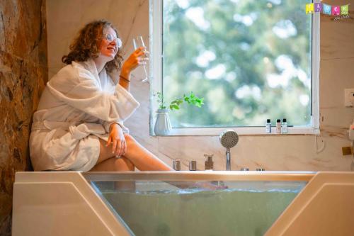 a woman sitting in a bath tub with a glass of wine at Flock Hostel Kathmandu in Kathmandu