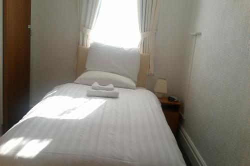 a white bed in a room with a window at Morrisy House in Blackpool