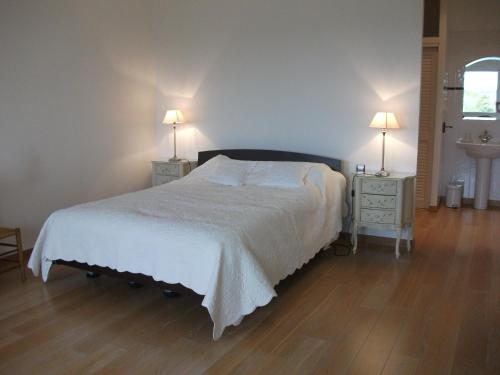 um quarto com uma cama branca e duas mesas de cabeceira com candeeiros em Camélia rouge em Granville