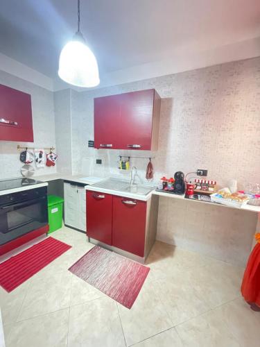 una cucina con armadi rossi e piano di lavoro bianco di Loft 46 a Brindisi