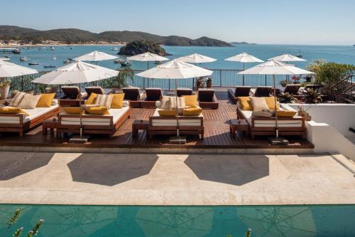 een groep stoelen en parasols naast een zwembad bij Casas Brancas Boutique Hotel & Spa in Búzios