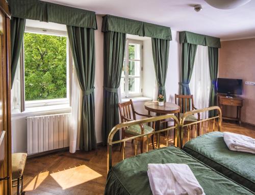 a bedroom with two beds and a table and a window at Hotel Roma Prague in Prague