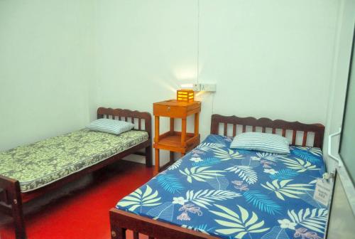 a room with two beds and a table with a night stand at Airport Tourist Resort in Katunayake