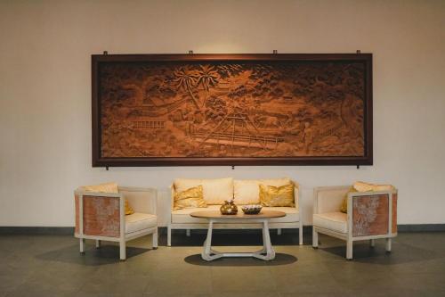 a table with two chairs and a painting on the wall at Tabebuya Resto & Resort in Kesembu