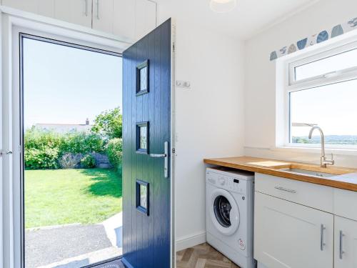 Una puerta azul en una cocina con lavadora en 3 bed property in Bude 78213 en Ashwater