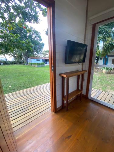 a screened in porch with a television and a table at Peixe Crew Manguinhos in Búzios