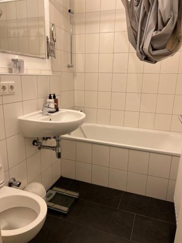 a bathroom with a sink and a toilet and a tub at Kölner City Stillvolle Apartment in Cologne