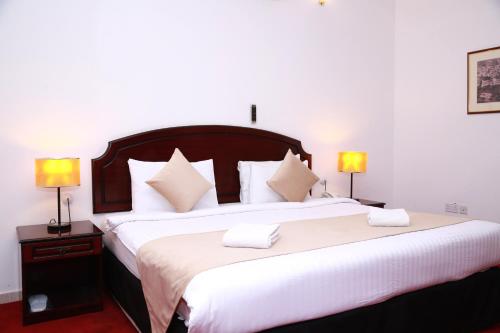 a bedroom with a large bed with two lamps at Ibri Oasis Hotel in ‘Ibrī