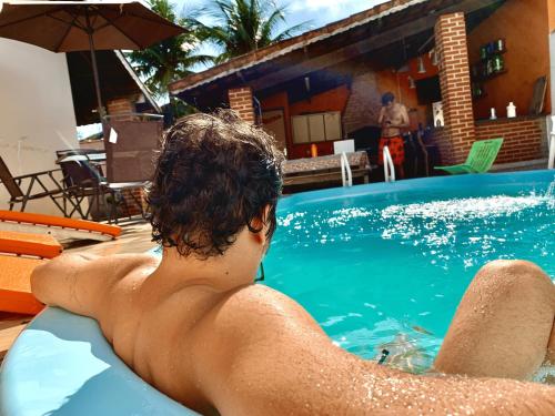 a man laying on a raft in a swimming pool at Guaru Surf Hostel in Guarujá