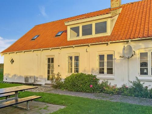 uma casa amarela com um telhado laranja e uma mesa de piquenique em Holiday Home Torbjörn - 2-5km from the sea in Bornholm by Interhome em Gudhjem