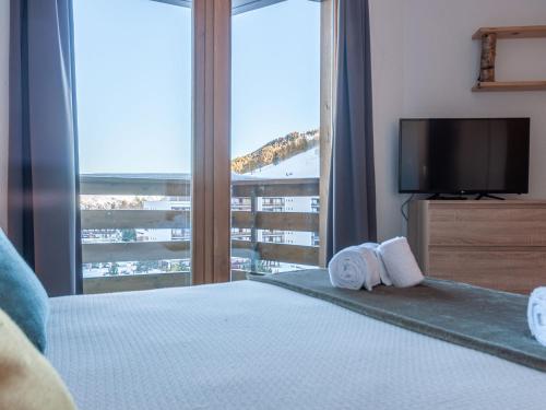 a bedroom with a bed with a television and a balcony at Apartment Mont-Fort 26 by Interhome in Siviez