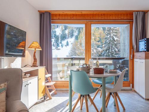 un soggiorno con tavolo, sedie e finestra di Apartment Mont-Fort-29 by Interhome a Siviez